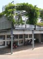 a two-story building with a garden on the roof and a parking area underneath