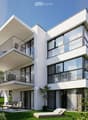 Modern, 2-story apartment building with large glass windows, balconies, and outdoor seating area