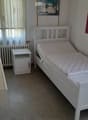 White bed frame, mattress, nightstand, wall decor with tropical beach scene