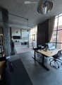 large open space, high ceilings, multiple large windows, office desk, office chairs, rug, metal shelves