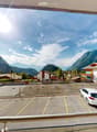 Mountainous surroundings, residential buildings, designated parking spots, greenery, parked white car, mountains in background