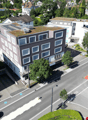 Aerial view of a multi-story building with several windows, a green roof, and an underground parking entrance.