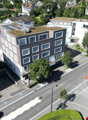 Aerial view of a multi-story building with several windows, a green roof, and an underground parking entrance.