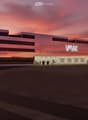Modern building with multiple floors, glass windows, central entrance, illuminated at dusk