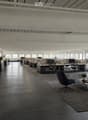 Modern office space with open-plan workstations, desks, chairs, and a lounge area featuring a sofa, coffee table, and chairs.