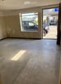 Empty room with tiled floor, wall damage, glass door and window, view of street and car.
