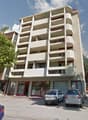modern multi-story building, balconies, parking area, glass doors, red frames