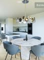 Marble table, round shape, modern chairs, central chandelier, white cabinets, black countertop, kitchen area with oven, modern furniture, wooden floor, windows with curtains