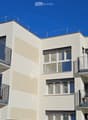Modern 3-story building, beige facade, large glass windows, balconies on each floor
