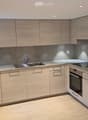 light wooden cabinetry, marble counter tops, stainless steel sink and faucet, integrated dishwasher, oven and microwave