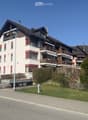 3 story apartment building, white and brown exterior, red shutters, balconies, street view