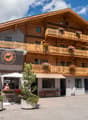 wooden exterior, multiple balconies, flag, parked cars, plants, awnings
