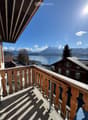 wooden balcony railing, wooden floor, view of a lake and mountains