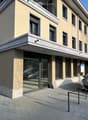 Modern building with glass facade, balcony, and parking area