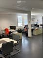 modern office space with desks, chairs, computer monitors, storage cabinets, and a table