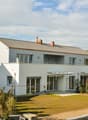 2 story house, white exterior, gray roof, large windows, balcony, garden, driveway