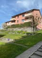 3 story house, pink exterior, multiple balconies, stone wall, green lawn, tree