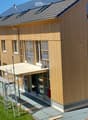 Newly constructed house, wooden exterior, solar panels on the roof, scaffolding around the building, construction crane nearby