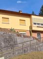 2 story house, yellow exterior, brown roof, stone wall, staircase, balcony, windows with shutters