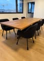 large wooden table, black chairs, wooden floor, large windows