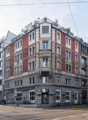 5 story building, red brick, white windows, balconies, awnings, street level shops