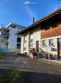 2 story house, white and brown exterior, wooden doors, windows, balcony, potted plants