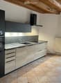 modern kitchen with wooden cabinetry, tiled flooring, black appliances, and a built-in oven, sink, and faucet
