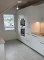 Kitchen. Modern kitchen with white cabinets, marble countertops, induction cooktop, and built-in oven and microwave.