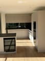 Modern kitchen with light-colored cabinets, black countertops, and wooden flooring. Features include a sink, faucet, oven, and dishwasher.