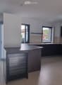 Modern kitchen with dark cabinets, a central island, and a built-in refrigerator. The space features large windows and a sleek, contemporary design.