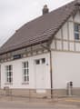 One story house, brown roof, white exterior, multiple windows, chimney, door, signs