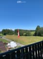 Balcony / Terrace. Balcony overlooking a rural landscape with a flagpole, cows, and a road.