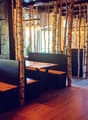 Restaurant interior with wooden tables, benches, and hanging lamps, featuring birch tree trunks as decorative columns.