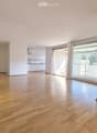 Unfurnished Room. Bright, unfurnished living space with wooden flooring, large windows, and a sliding glass door leading to a balcony.