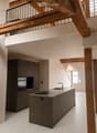 Kitchen. Modern kitchen with a central island, stainless steel sink, faucet, built-in oven, and dark grey cabinets. Exposed wooden beams and a balcony overlook the space.