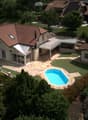 Aerial view of a residential area with multiple houses, a swimming pool, and well-maintained gardens.