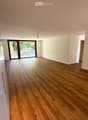 large windows, wooden floor, sliding glass door, balcony, white walls, bright lighting