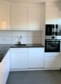 Modern kitchen with white cabinets, stainless steel appliances, and a black countertop.