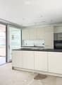 Modern kitchen with white cabinets, black countertop, sink, faucet, and built-in oven. Large sliding glass door provides access to an outdoor area.