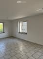 Empty room with tiled floor, three windows, and white walls. No furniture or equipment present.