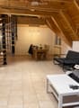 Modern living room with exposed wooden beams, a spiral staircase, a sofa, a coffee table, a dining table with chairs, and a futon.