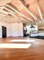 {"visible_features": [],    "type": "Room",    "description": "Open kitchen with modern appliances, wooden floors, white walls, wooden beams, refrigerator, cabinets, central island with sink and stove",    "localized_descriptions":        {        "E