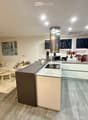 Modern open-plan living and kitchen area with a sofa, coffee table, kitchen island, and various appliances.