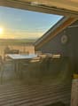Wooden deck with a table and chairs, overlooking a scenic landscape at sunset.