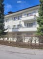 white exterior with windows, balcony on first floor, wooden fence