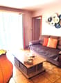 Living room with a grey sofa, orange cushions, a wooden coffee table, a floor lamp, and decorative plates on the wall.