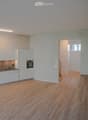 empty kitchen with built-in appliances, white cupboards, wooden floor