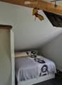 sloped ceiling, bed, bedside table, window, wardrobe, bulletin board, mounted television, pin cushion
