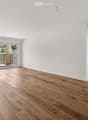 Empty room with light wooden flooring, white walls, and large sliding glass doors leading to a balcony.