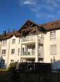 modern apartment building, white walls, brown roof, multiple balconies, chimneys